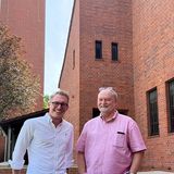 Zwei Männer vor der modernen Backsteinkirche stehend